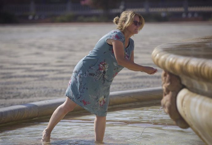 Una mujer se refresca en la fuente de la Plaza de España durante el aviso naranja por calor