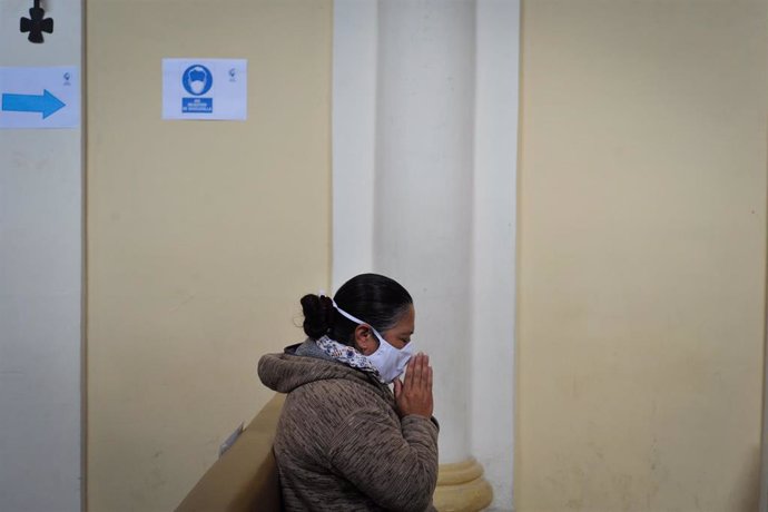 Una mujer rezando con mascarilla por el coronavirus en Quito. 
