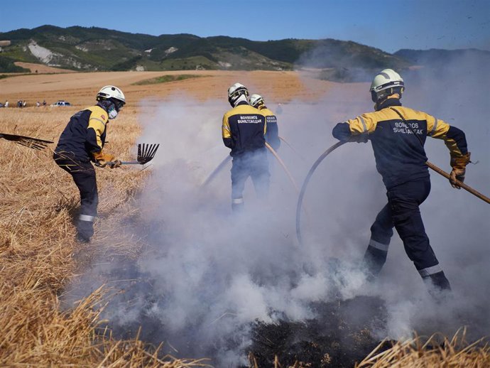 Varios bomberos realizan labores de extinción de un incendio forestal producido en una zona de campo de cereal, sin afectar a zonas urbanas, cerca de la localidad navarra de Sarriguren, a 21 de junio de 2020.