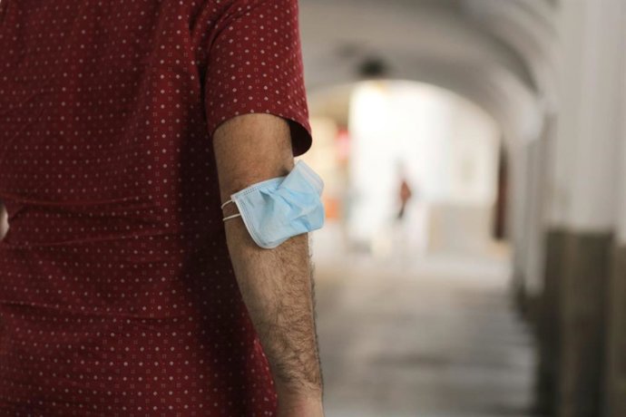 Un hombre lleva la mascarilla en el brazo en Mérida