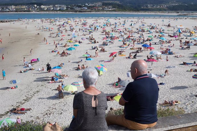 Dos personas observan la playa en A Mariña (Lugo/Galicia) a 27 de julio de 2020. La comarca mantiene este domingo 51 casos activos de COVID-19 tras una nueva alta y un nuevo contagio con respecto al sábado.