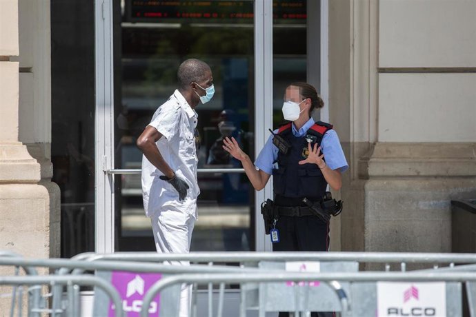 Un Mosso d'Esquadra habla con un hombre en la entrada de la Estación de Tren de Lleida, capital de la comarca del Segri, en Lleida, Catalunya (España), a 6 de julio de 2020. El presidente de la Generalitat, Quim Torra, anunció el pasado sábado el confi