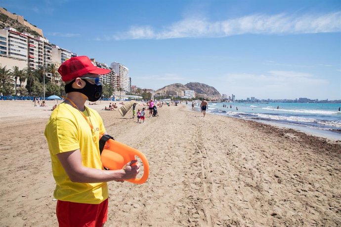 Un socorrista protegido con mascarilla vigila la Playa del Postiguet, de archivo.
