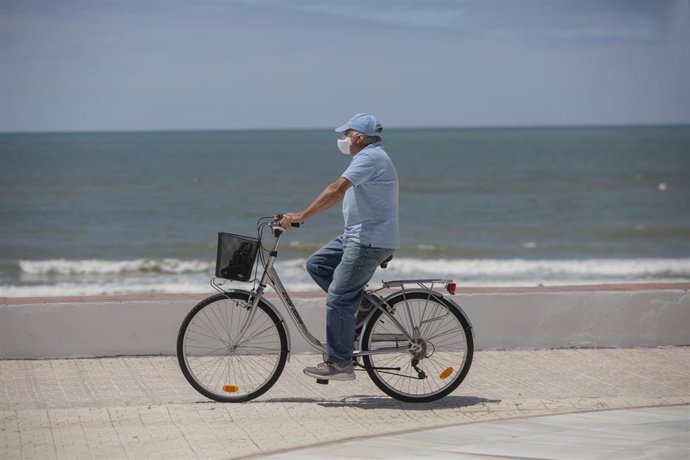Un hombre en bicicleta paseando por el paseo marítimo de la playa de Matalascañas.