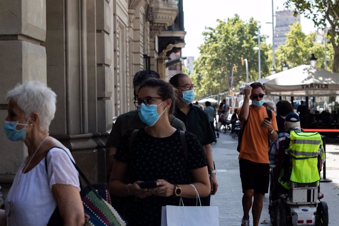 Desenes de persones protegides amb mascarilla fan cua per entrar en una biblioteca, a Barcelona, Catalunya (Espanya), a 23 de juliol de 2020.