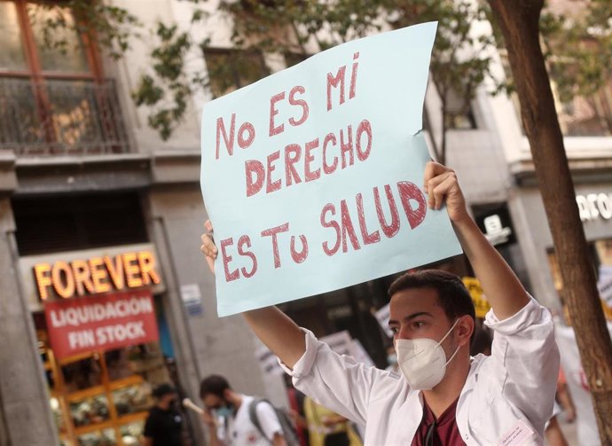 Un joven levanta una pancarta en la que se lee 'No es mi derecho es tu salud' durante una manifestación de los médicos internos residentes (MIR) en Madrid (España), a 27 de julio de 2020. La concentración es para transmitir a la Consejería de Sanidad qu