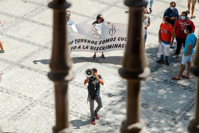 Un hombre con un megáfono perteneciente al sector taurino protesta junto a otras personas a las puertas del Ayuntamiento de Toledo a la llegada de la ministra de Trabajo, Yolanda Díaz, a quien han recibido con pitos y con gritos de "dimisión"