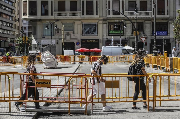 Tres personas pasan al lado de las vallas de obras en la Plaza de San Agustín de Valencia, Comunidad Valenciana (España), a 27 de julio de 2020. 