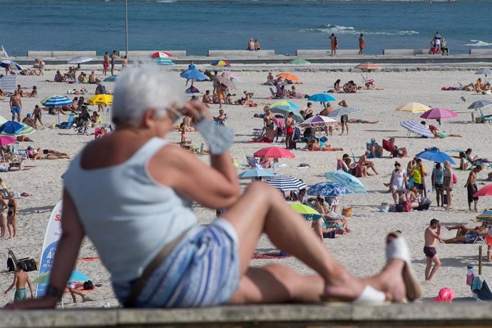 Una persona sentada frente a la playa en A Mariña  