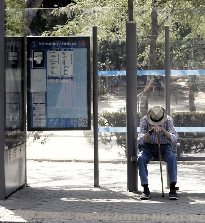 Un pensionista espera el autobús en la marquesina de una parada de Madrid.