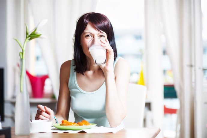 Mujer bebiendo leche en el desayuno.