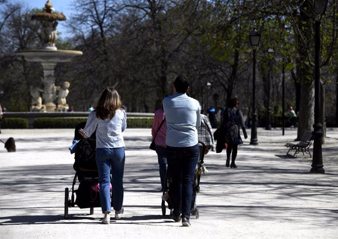 Unos padres pasean a sus hijos en sillitas de bebé por el Parque del Retiro en el primer día sin colegio por el riesgo del coronavirus, en Madrid (España) a 11 de marzo de 2020.