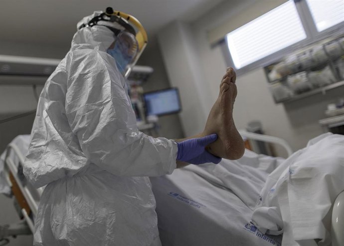 Personal sanitario totalmente protegido atiende a un paciente ingresado en la Unidad de Cuidados Intensivos del Hospital Infanta Sofía en San Sebastián de los Reyes (Madrid).
