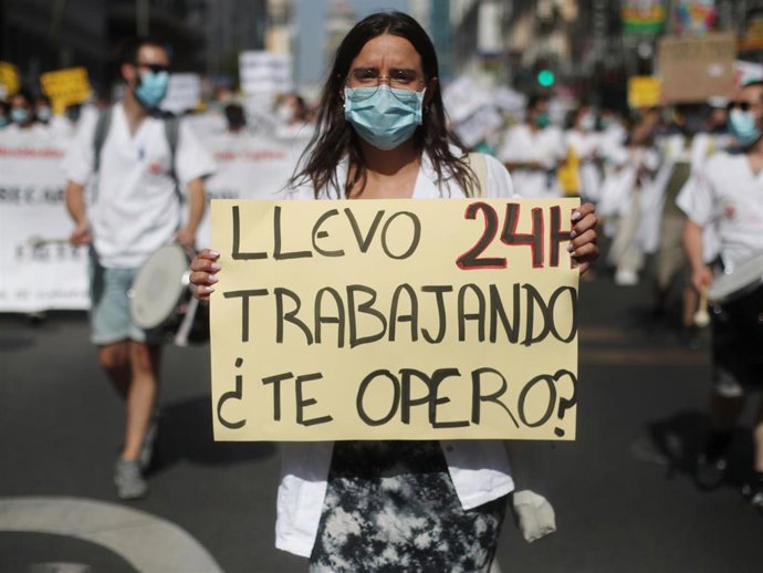 Una mujer sujeta una pancarta en la que se lee 'Llevo 24h trabajando, ¿te opero?' durante una manifestación de los médicos internos residentes (MIR) en Madrid (España)