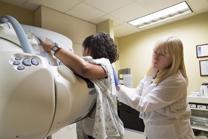 Un técnico de radiología ayuda a preparar a una paciente para una mamografía de detección en el UW Medical Center-Roosevelt en Seattle, Washington.