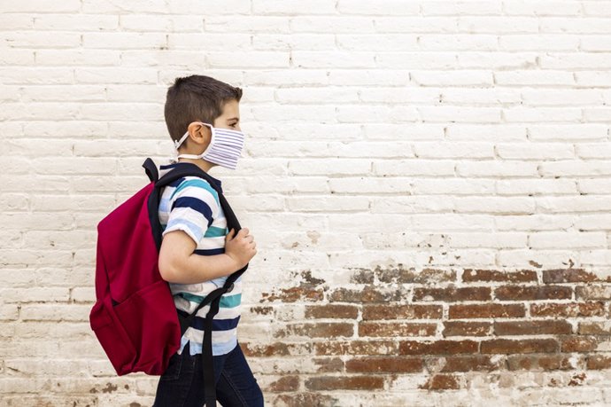 Niño con mascarilla andando al colegio.