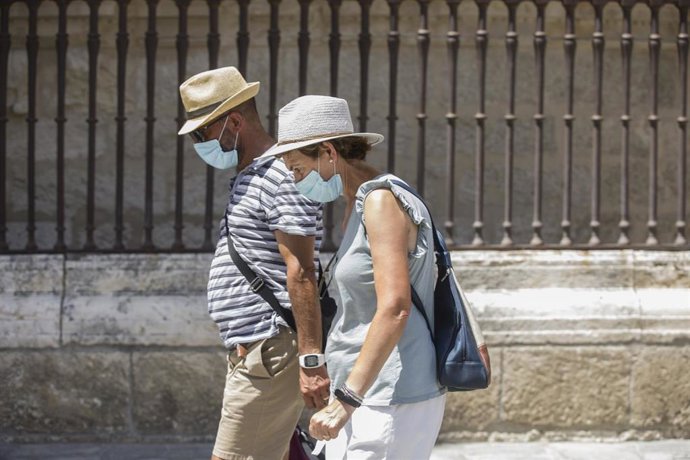 Dos personas caminan con mascarilla y sombrero durante la ola de calor africano que ha llegado este jueves a España.