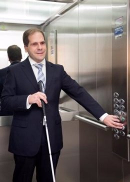 Una persona con ceguera acciona el botón de un ascensor