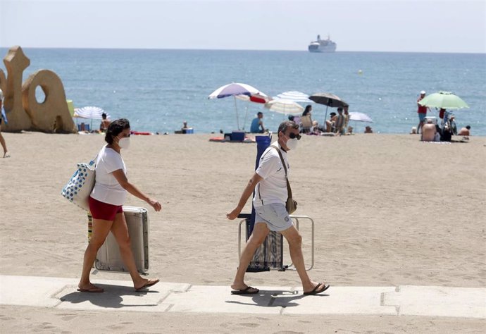 Dos personas con mascarilla acceden a la playa de La Malagueta. En Málaga (Andalucía, España), a 19 de julio de 2020.