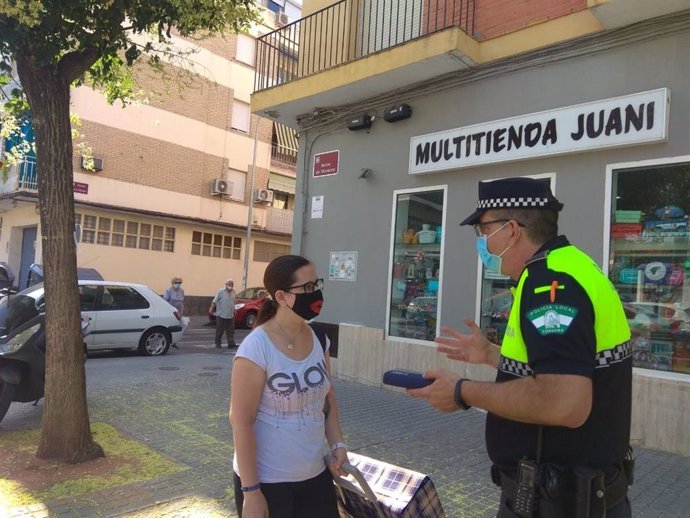 Un policía local de Córdoba habla con una ciudadana sobre el uso obligatorio de la mascarilla.