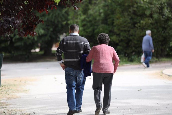 Un hombre acompaña a una mujer de edad avanzada a pasear.