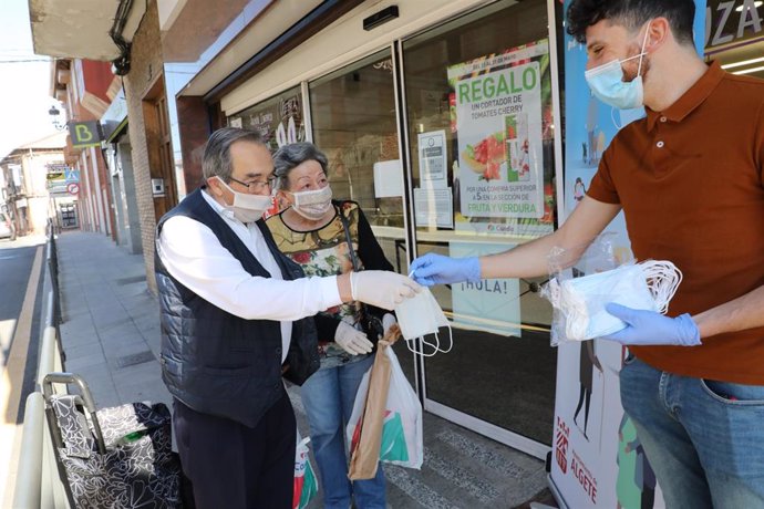 Reparto a dos clienes de mascarillas a la puerta de un Supermercado en Algete (Madrid)  