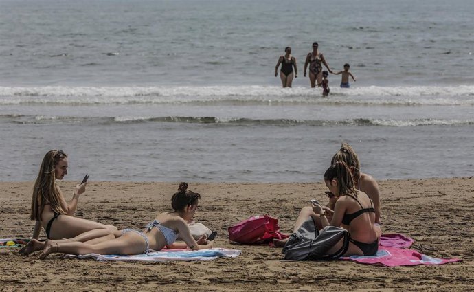 Bañistas en la Playa de la Malvarrosa, con bandera verde durante el primer día de la Fase 2