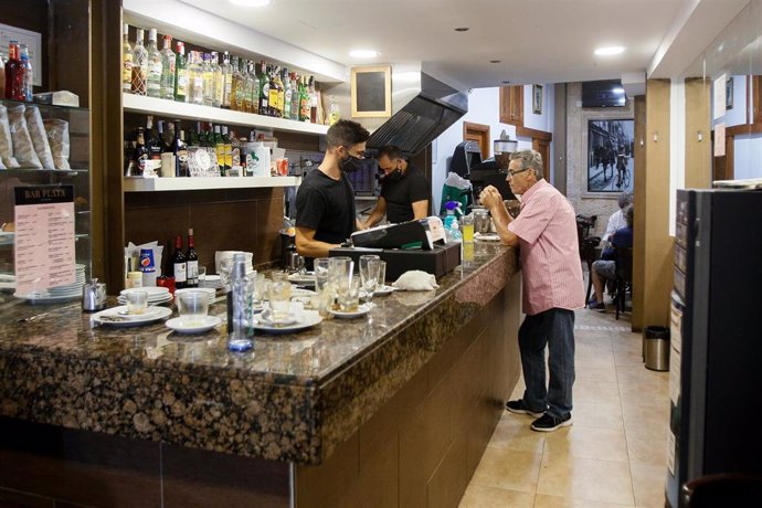 Camareros trabajando en la barra del interior de un bar en Palma.