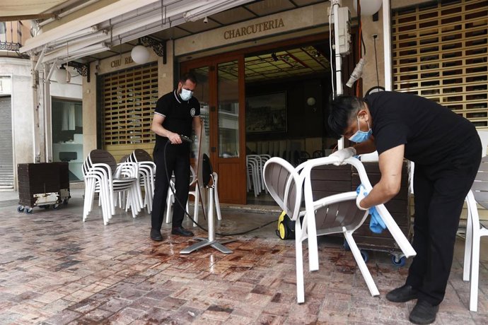 Trabajadores de la cafetería Central ubicada en la Plaza de La Constitución, en Málaga se afanan en la limpieza de los enseres de la terraza a consecuencia del virus COVID-19. Málaga a 20 de mayo del 2020
