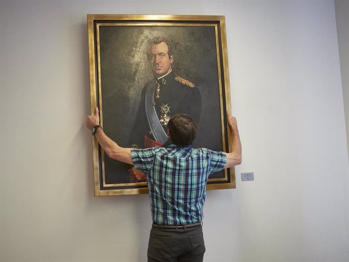 Un operario retira el retrato del rey emérito Juan Carlos I de la Sala de Gobierno del Legislativo foral del Parlamento de Navarra