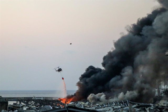 04 August 2020, Lebanon, Beirut: A military helicopter tries to put out a fire at the site of a massive explosion in Beirut's port. Photo: Marwan Naamani/dpa
