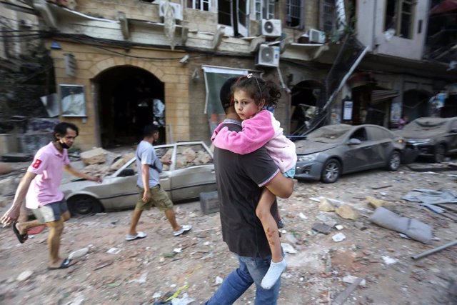 Un hombre evacúa a una niña tras las explosiones en Beirut