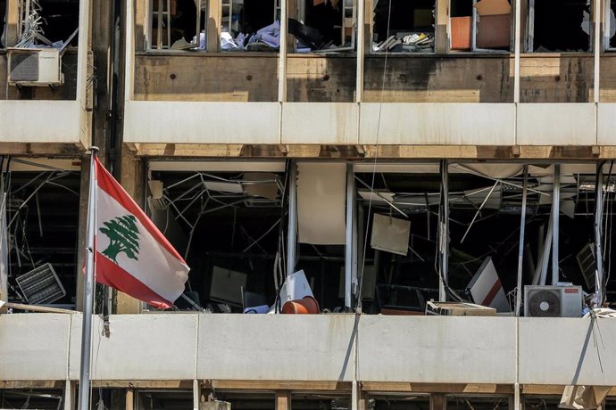 Una bandera de Líbano frente a un edificio dañado por las explosiones en el puerto de Beirut