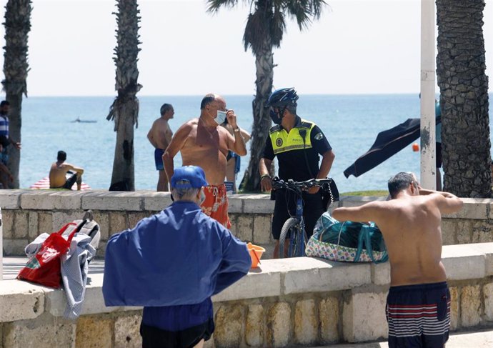 Policía Local informa a un bañista en la playa de La Malagueta. En Málaga (Andalucía, España), a 19 de julio de 2020.