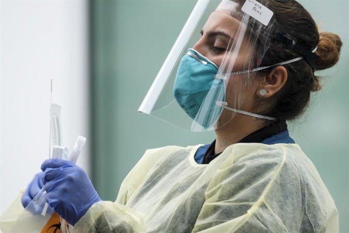 03 August 2020, US, Los Angeles: A health worker wearing a protective suit demonstrates how to take a coronavirus test at a mobile Coronavirus testing center at Martin Luther King Jr. Community Hospital. Photo: Ringo Chiu/ZUMA Wire/dpa