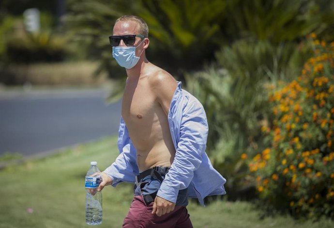 Un hombre con el torso descubierto y gafas de sol camina por la calle