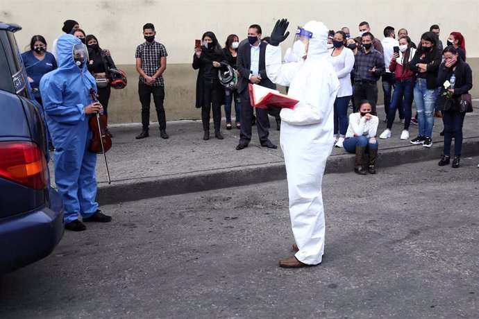 Un cura ataviado con un traje protector habla durante el funeral de una víctima de la COVID-19 en Bogotá, Colombia. 