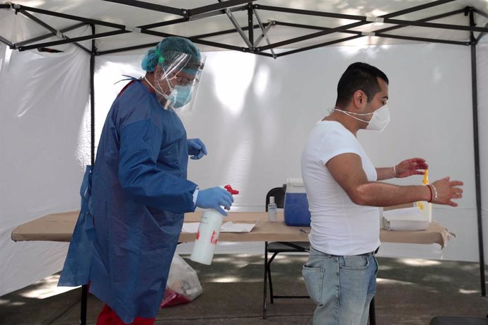 Un trabajador sanitario desinfecta a un hombre antes de someterle a la prueba de la COVID-19 en las instalaciones levantadas en el parque Salesiano de Ciudad de México.
