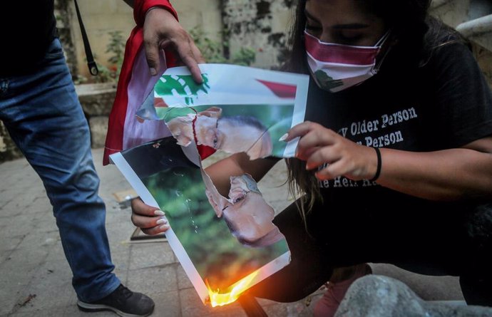 Una manifestante quema la imagen del presidente de Líbano, Michel Aoun