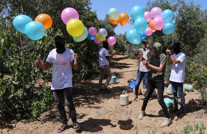 Palestinos se preparan para lanzar globos incendiarios desde Gaza a Israel.
