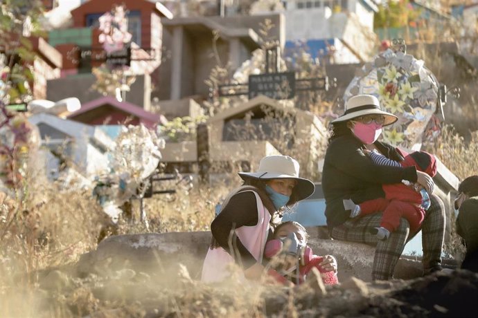 Dos mujeres esperan en un cementerio de la ciudad de Arequipa, en el sur de Perú, a que dé comienzo el servicio religioso por la muerte de un enfermo de coronavirus.