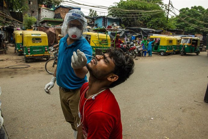 Un trabajador de los equipos sanitarios somete a un ciudadano de Nueva Delhi a una prueba de detección de COVID-19.