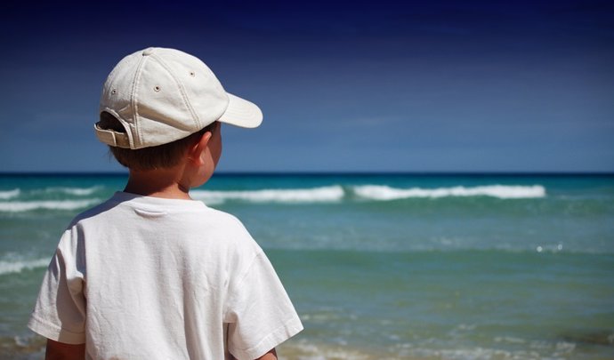 Niño con gorra en la playa.
