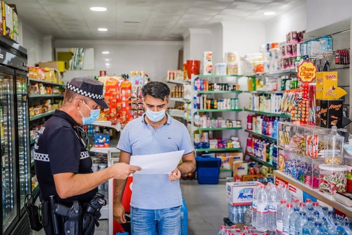 Un agente de la Policía Local reparte cartelería con información sobre la normativa anticovid-19