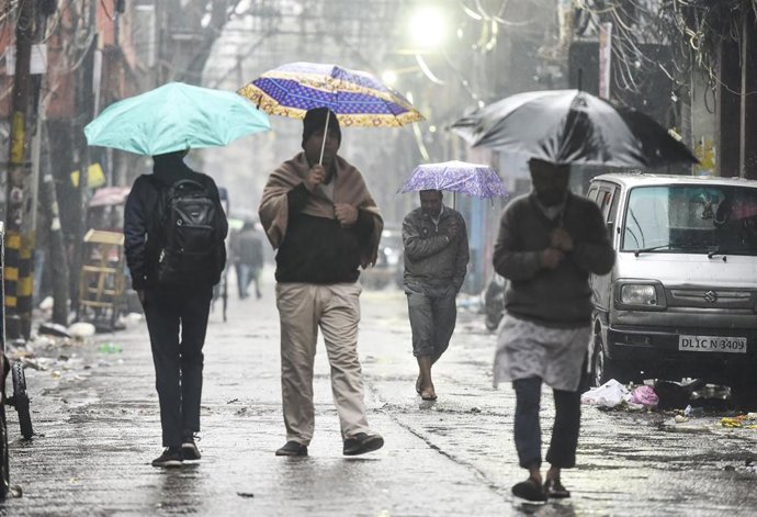 Imagen de archivo de varios transéuntes durante las fuertes lluvias monzónicas en India. 