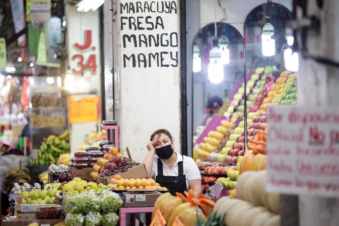 Una mujer en un puesto de frutas en un mercado en México
