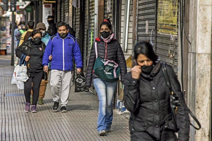 Un grupo de personas ataviados con mascarillas circulan por una céntrica calle de la ciudad de Buenos Aires. 