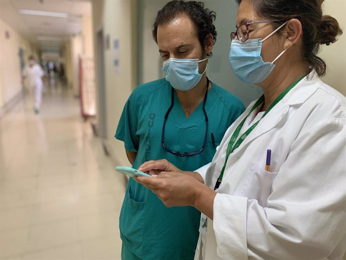 Dos profesionales sanitarios consultan un teléfono móvil