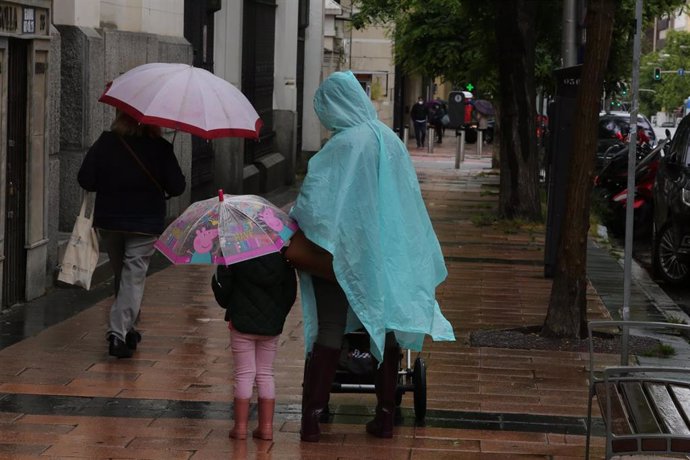 Una mujer y una niña pasean con paraguas en Madrid