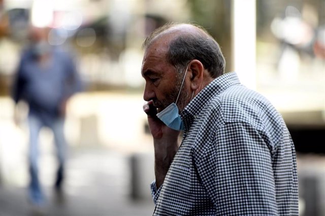 Un hombre con mascarilla habla por teléfono en la Comunidad de Madrid.